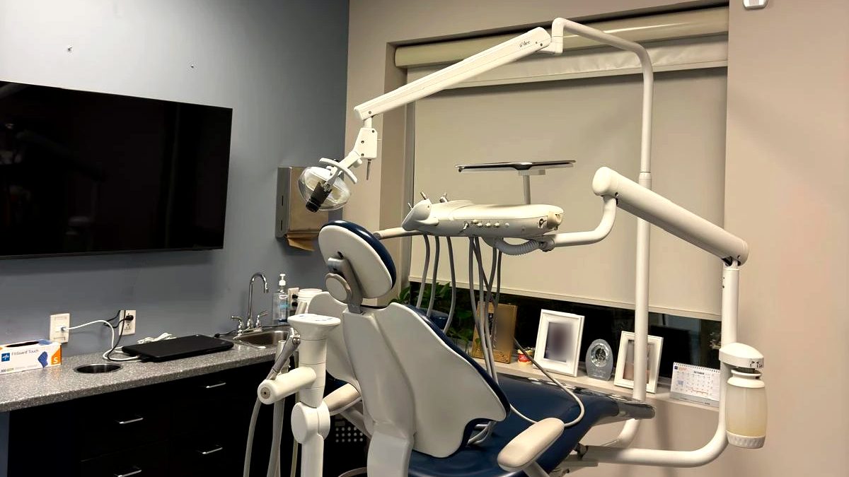 Another treatment room at the clinic, with a navy dental chair by the window